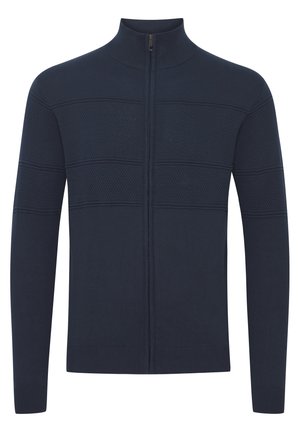 Mornarsko modra jopica na zips z teksturiranimi čelni in rebrastimi manšetami. Ima visok ovratnik in prilega silhueto. Mehka pletenina.