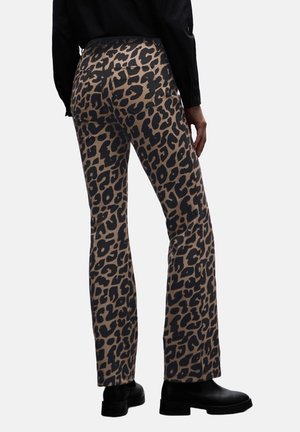 Pantaloni svasati animalier beige e neri, realizzati in un tessuto morbido, con due tasche posteriori e vita media. Indossati con stivali neri.