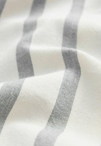 Platno od lana s bijelom pozadinom i naizmjeničnim sivim prugama. Tekstura izgleda mekano i tkanje je vidljivo s očiglednim nitima.