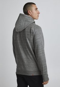 Sudadera gris con un acabado texturizado, capucha ajustable con cordón y puños acanalados. Estilo de corte relajado con un acento de logo cerca del dobladillo.