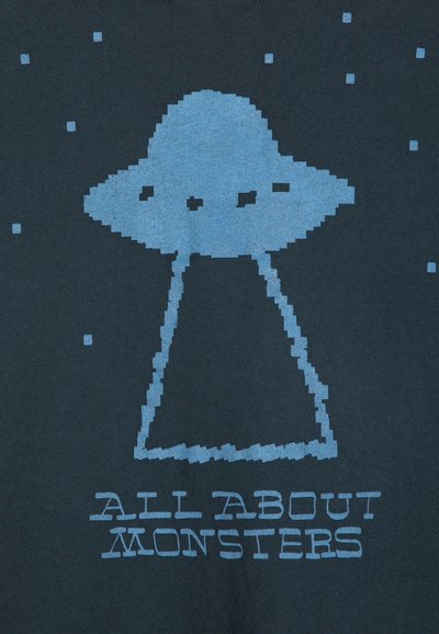 OVNI bleu pixellisé avec des faisceaux lumineux vers le bas entouré de petits carrés, avec le texte "ALL ABOUT MONSTERS" en dessous sur fond sombre.