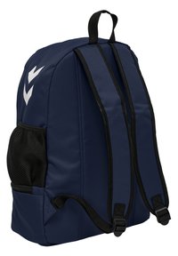 Dunkelblauer Rucksack aus glattem, strapazierfähigem Stoff, mit schwarzen Trägern, einer seitlichen Netztasche und weißen Chevron-Grafiken auf der Vorderseite.