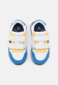 Baskets blanches avec des accents bleus, jaunes, gris et rouges. Comprend des doubles bandes Velcro, des pointes arrondies et des semelles texturées. Taille 24.