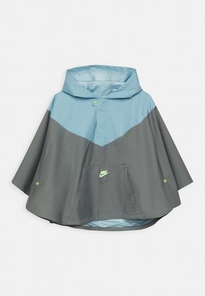 Poncho à capuche Nike bleu clair et gris, avec poche avant et boutons-pression sur les côtés et le col.