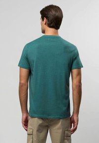 Miętowozielony t-shirt z krótkim rękawem i okrągłym dekoltem, wykonany z miękkiego materiału, o gładkiej fakturze i luźnym kroju, widziany od tyłu.