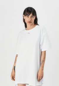 Bílé oversized tričko šaty vyrobené z bavlny, s kulatým výstřihem, krátkými rukávy a malou logem na hrudi.