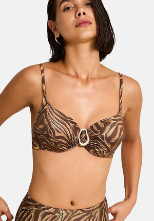 Femme portant un haut de bikini marron à imprimé animal avec une boucle ovale centrale en métal doré et un bas taille haute assorti.