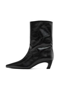Bottine noire en cuir à bout pointu avec un talon moyen. Texture lisse avec de légères rides, présentant une silhouette épurée et un design minimaliste.
