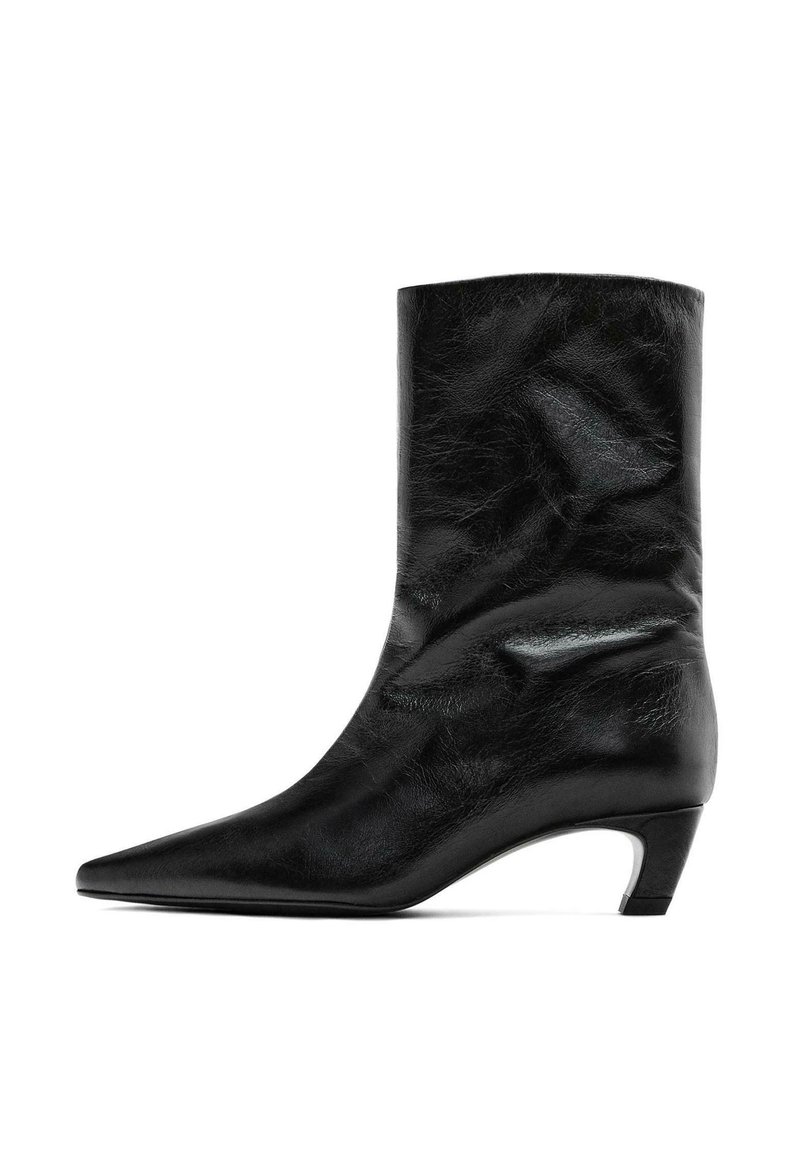 Černý kožený kotníkový bot s špičatou špičkou a středním podpatkem. Hladký povrch s jemnými vráskami, s elegantním siluetou a minimalistickým designem.