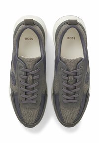 Paar graue BOSS-Sneakers mit Obermaterial aus Wildleder und Stoff, grauen Schnürsenkeln und weißer Sohle, von oben auf einem weißen Hintergrund betrachtet.
