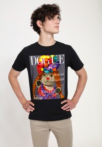 Černé tričko s lesklou grafikou psa podobného charakteru s copy a barevným květinovým věnečkem. Výrazný název časopisu "DOGUE".