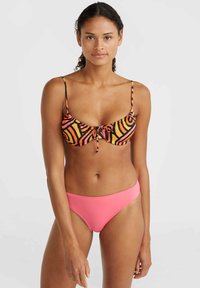Bikini komplet z črnim zgornjim delom z oranžnimi in roza spirali ter roza spodnjim delom. Zgornji del ima tanke naramnice in podrobnost z vezanjem spredaj.