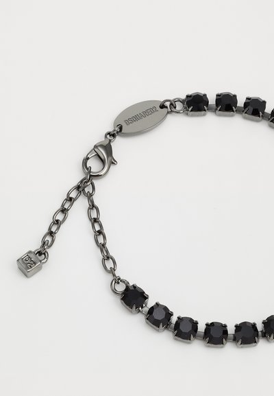 Bracelet en pierres noires avec des pierres octogonales dans un métal de ton argent, avec un fermoir en homard et une étiquette gravée.