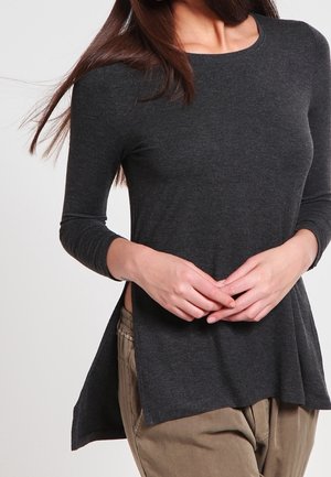 Top a maniche lunghe grigio scuro con scollo rotondo, spacchi laterali e vestibilità rilassata, realizzato in tessuto morbido. Abbinato a pantaloni kaki.