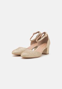 Gold glitter ankle strap heels with a block heel, pointed toe, and a soft inner lining for comfort. Features a buckle closure detail.