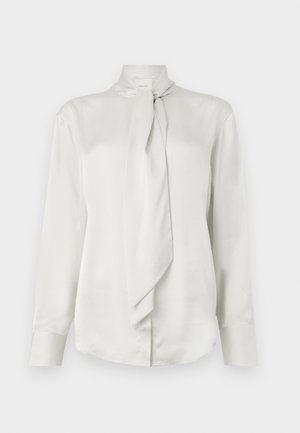 Weiße Bluse mit langen Ärmeln, hohem Kragen und einer vorne gebundenen Schärpe, aus glattem, satinähnlichem Stoff.