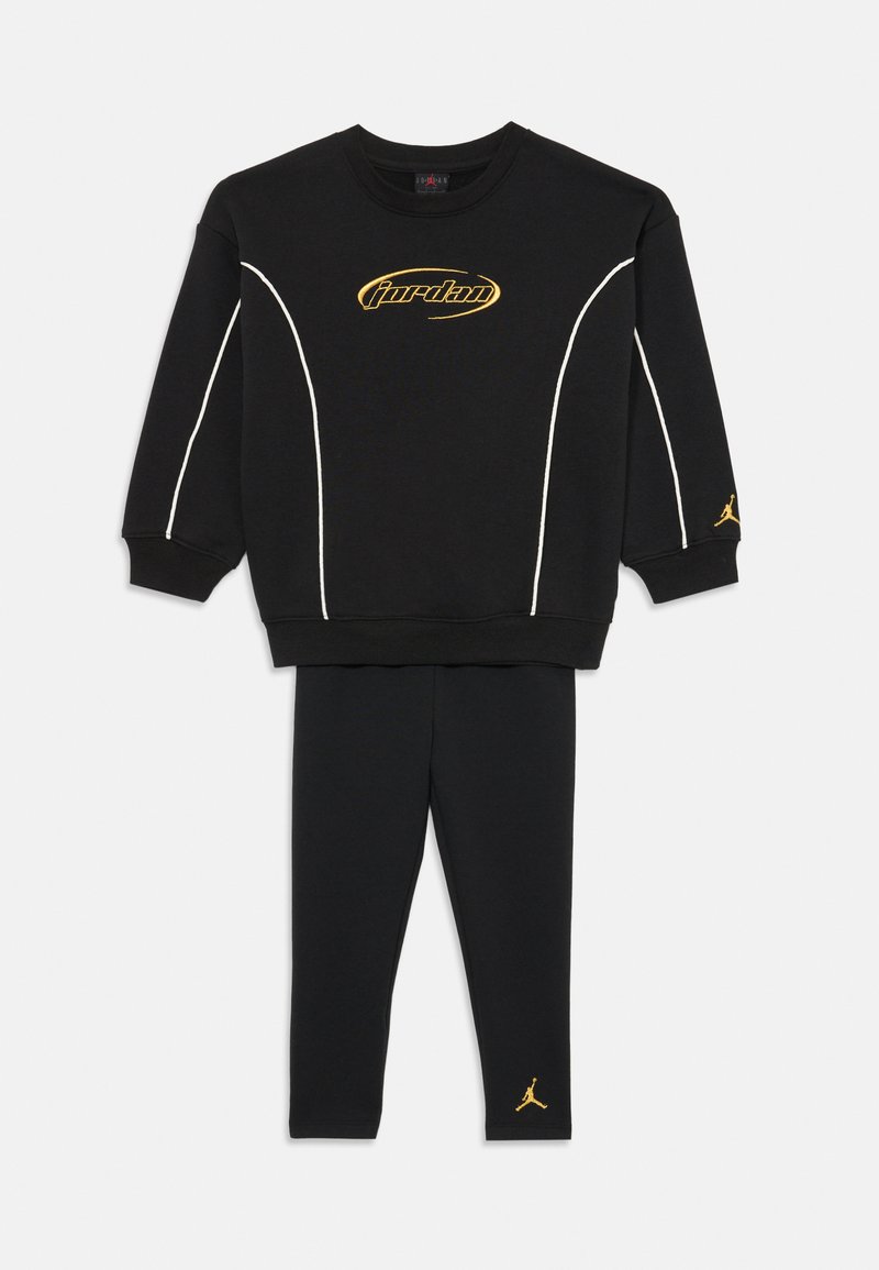Tricou de trening negru cu accente albe, logo auriu "Jordan" pe piept, asortat cu colanți negri cu un mic logo auriu la gleznă.