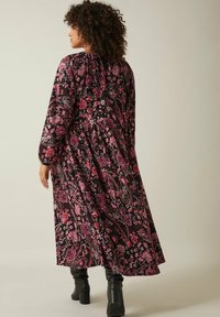 Robe maxi avec un fond noir orné de motifs floraux et paisley roses, des manches élastiques à poignets, et une taille froncée.