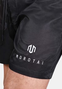 Černé sportovní šortky vyrobené z lehkého materiálu. Obsahují elastický pás, šňůrku na stažení a vyšitý bílý logo "MOROTAI".