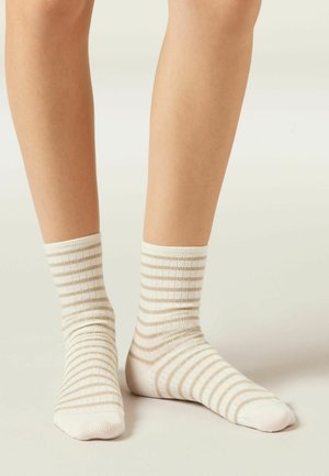 Beige och vita randiga bomullssockor med ribbad textur, ankellång design och enfärgade vita stånd.