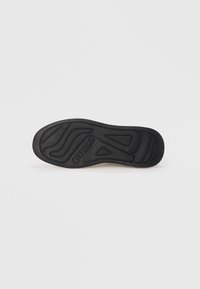Black rubber shoe sole featuring curved lines and textured patterns, with "GUESS" logo embossed near the center.