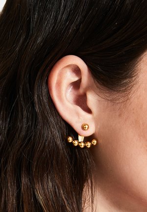 Boucles d'oreilles en ton or avec un petit clou rond et une section inférieure ornée de cinq perles sphériques dans un design incurvé.