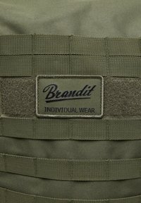 Olivno zelena taktična obleka z vodoravno mrežico in tkaninsko obližem z oznako "Brandit Individual Wear." Opremljena je z Velcro detajli za pritrditev.