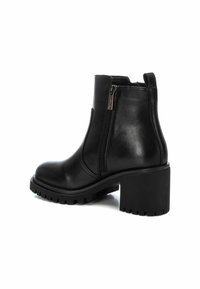 Botas de cuero negro hasta el tobillo con un tacón grueso. Cuentan con un zipper lateral y una suela texturizada para mayor agarre. Acabado suave con acentos mínimos.