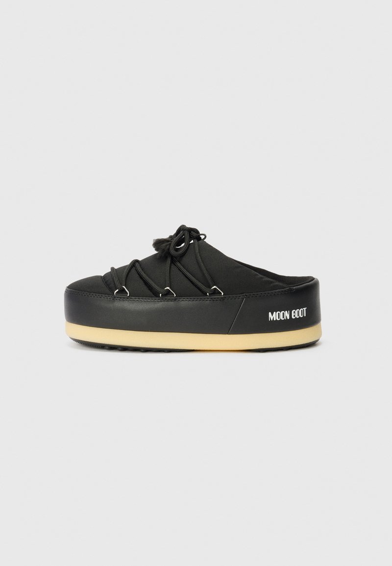 Chaussure noire à enfiler avec un bout arrondi, des lacets élastiques et une semelle plate-forme beige clair. Présente la marque "MOON BOOT" sur le côté.
