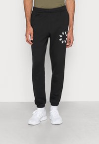 Pantaloni della tuta neri con vita elastica, con accenti del logo bianco coscia e caviglie a coste. Realizzati in tessuto morbido.