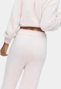 Różowy, puszysty zestaw odzieży domowej z cropped topem z oversize'owymi rękawami oraz spodniami z wysokim stanem, wykonanymi z miękkiego, teksturowanego materiału.