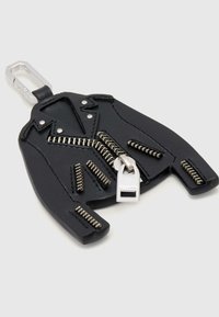 Czarny brelok w kształcie kurtki motocyklowej z srebrnymi detalami zamka błyskawicznego i srebrnym karabińczykiem na jasnym tle.