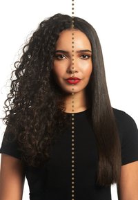 Vrouw met half krullend, half steil donker haar, gekleed in een zwarte top, met rode lippenstift, en een verticale gestreepte lijn die haar gezicht en haar scheidt.