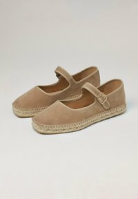 Espadrilles en daim beige avec un bout rond, une bride à la cheville et une semelle en jute tissée. Texture lisse avec un design plat et des embellissements minimalistes.