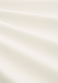 Crème stof met een gladde, zachte textuur, met subtiele plooien en een matte afwerking, uitgelicht tegen een neutrale achtergrond.