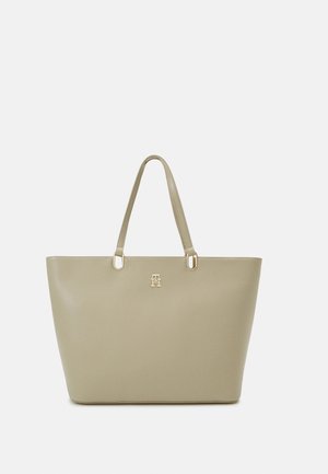 Beige tote bag made of smooth synthetic material, featuring two top handles and a gold-tone logo accent on the front.