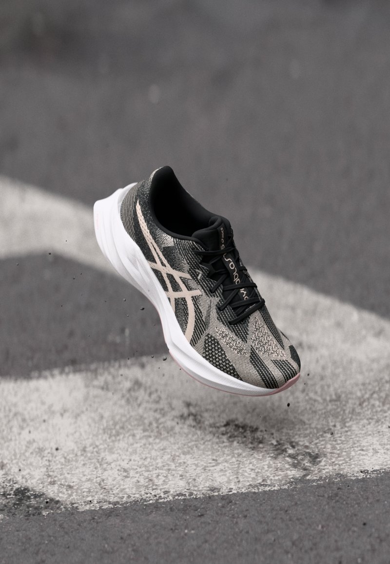 Schwarze und graue Laufschuhe mit einer strukturierten Oberseite, die ein Schnürdesign aufweisen und eine weiße Sohle haben. Mit reflektierenden Details akzentuiert.