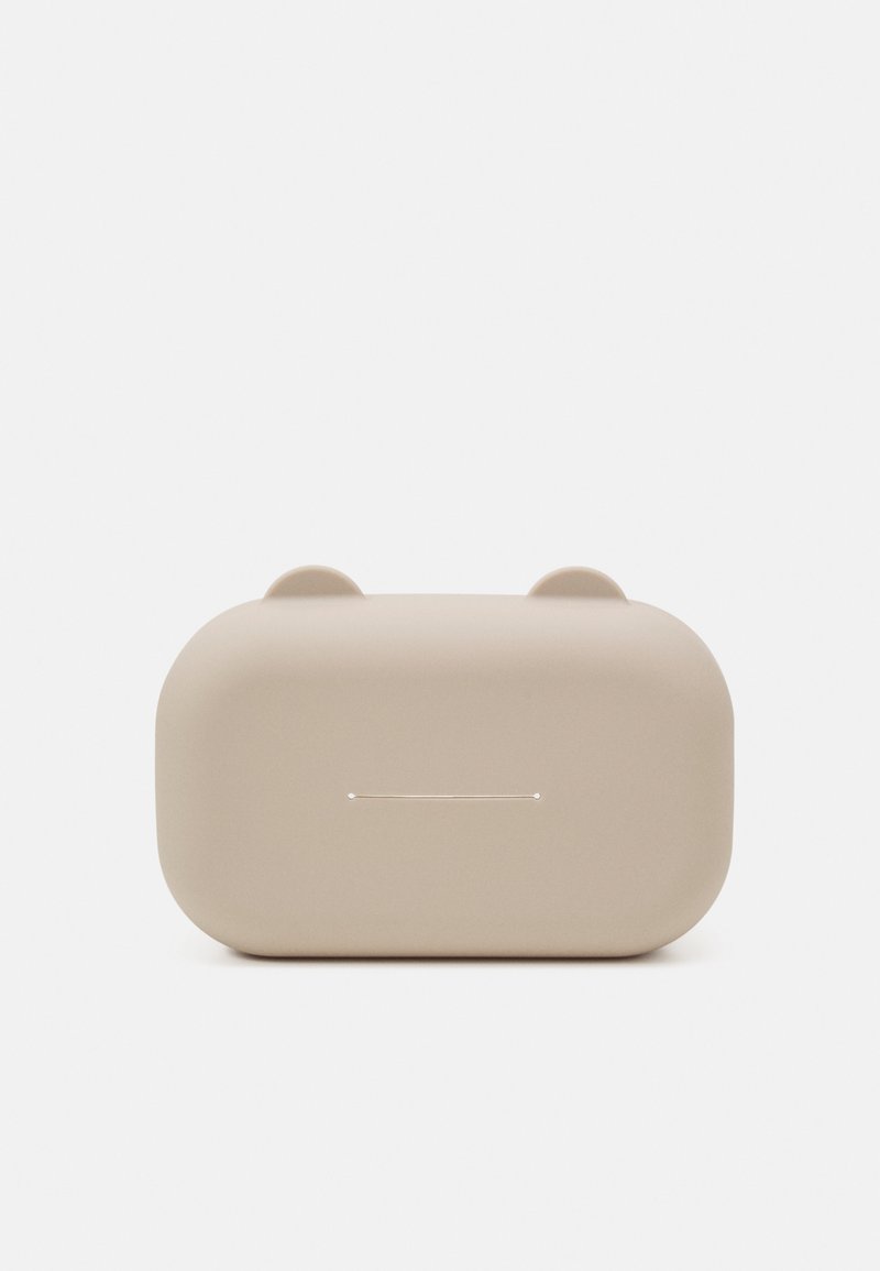 Μπεζ θήκη ακουστικών με στρογγυλεμένες γωνίες, η οποία διαθέτει μίνιμαλ σχεδίαση και διακριτές προεξοχές στην κορυφή. Η κεντρική γραμμή υποδεικνύει τον μηχανισμό ανοίγματος.