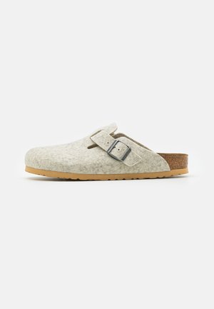 Gray felt clogs with a rounded shape and a side buckle. Brown textured cork footbed and a flexible rubber outsole. Simple, open design.