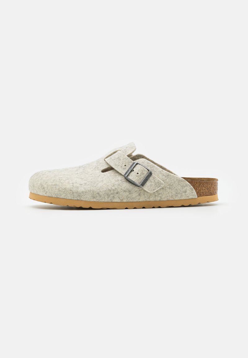 Tamancos cinzentos com forma arredondada e fivela lateral. Palmilha de cortiça texturizada em castanho e sola de borracha flexível. Design simples e aberto.