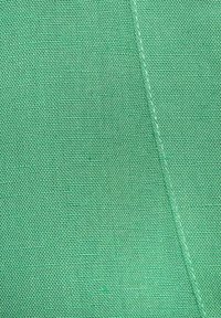 Bright green fabric with a textured weave pattern, featuring diagonal stitching detail along one edge, enhancing its tactile quality.
