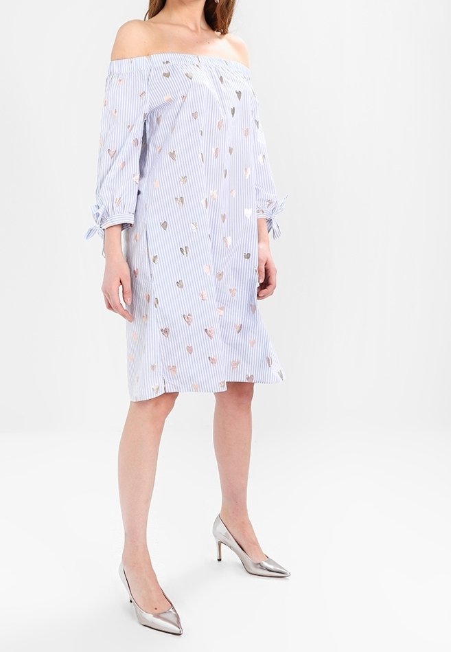 Olkapäältä tippuva mekko, jossa on sinivalkoiset raidat, koristeltu metallinhohtoisilla sydänkuvioilla, ja jossa on kolme neljäosaa hihat sekä nauhat hihoissa.