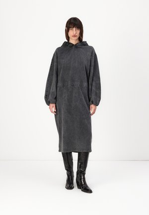 Oversized gray hooded dress made of denim-like fabric, featuring a cinched waist and long sleeves with elastic cuffs. Black tall boots.
