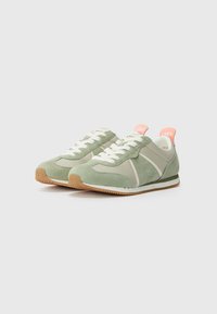 Sneaker verde in suede con accenti grigio chiaro e lacci bianchi. Presenta un tallone rosa con la scritta '1964' e una suola in gomma texturizzata.