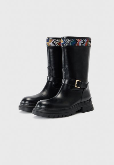 Black leather boots with a chunky sole, featuring a decorative colorful woven band at the top and a side buckle accent.