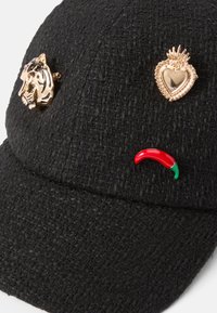 Cască de baseball texturată neagră, cu accesorii metalice în formă de tigru și inimă, plus un accent de ardei iute roșu și verde.