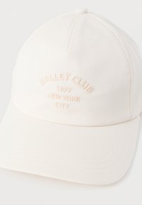 Λευκό καπέλο μπάσκετ από βαμβάκι με καμπυλωτή γείσο. Διακοσμημένο με κεντημένο κείμενο: "Ballet Club 1977 New York City" σε ανοιχτό ροζ χρώμα.