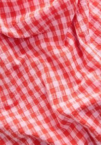 Rood en roze geblokt stof met een zachte, lichte textuur, met een rasterpatroon van afwisselend volle vierkanten.