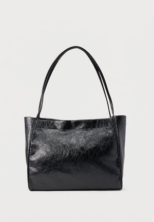 Sac fourre-tout en cuir noir avec deux sangles d'épaule et une surface lisse légèrement texturée sur un fond uni.