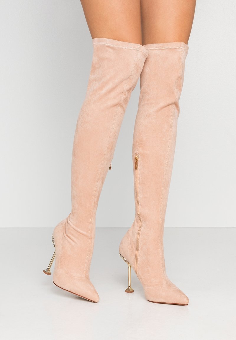 Blushrosa över knäboots i mjuk mocka med spetsig tå och metallisk stilettklack. Har en sidogylf för enkel på- och avtagning.